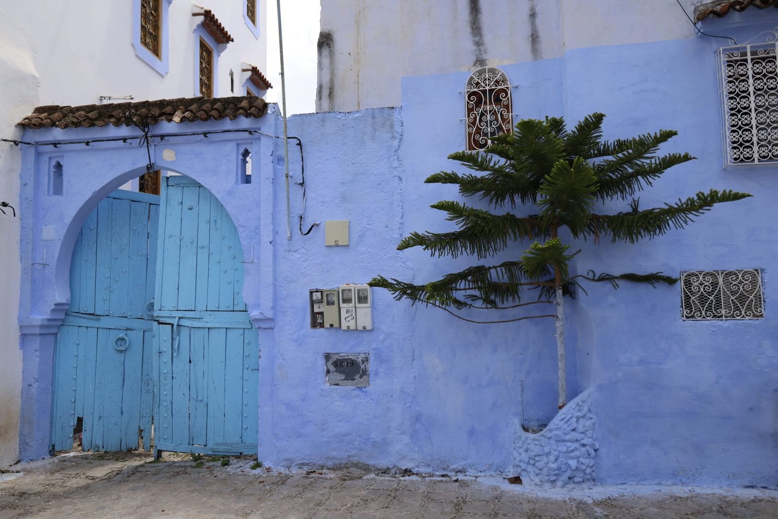 Un arco dipinto di blu e una porta in legno intagliato in una città marocchina