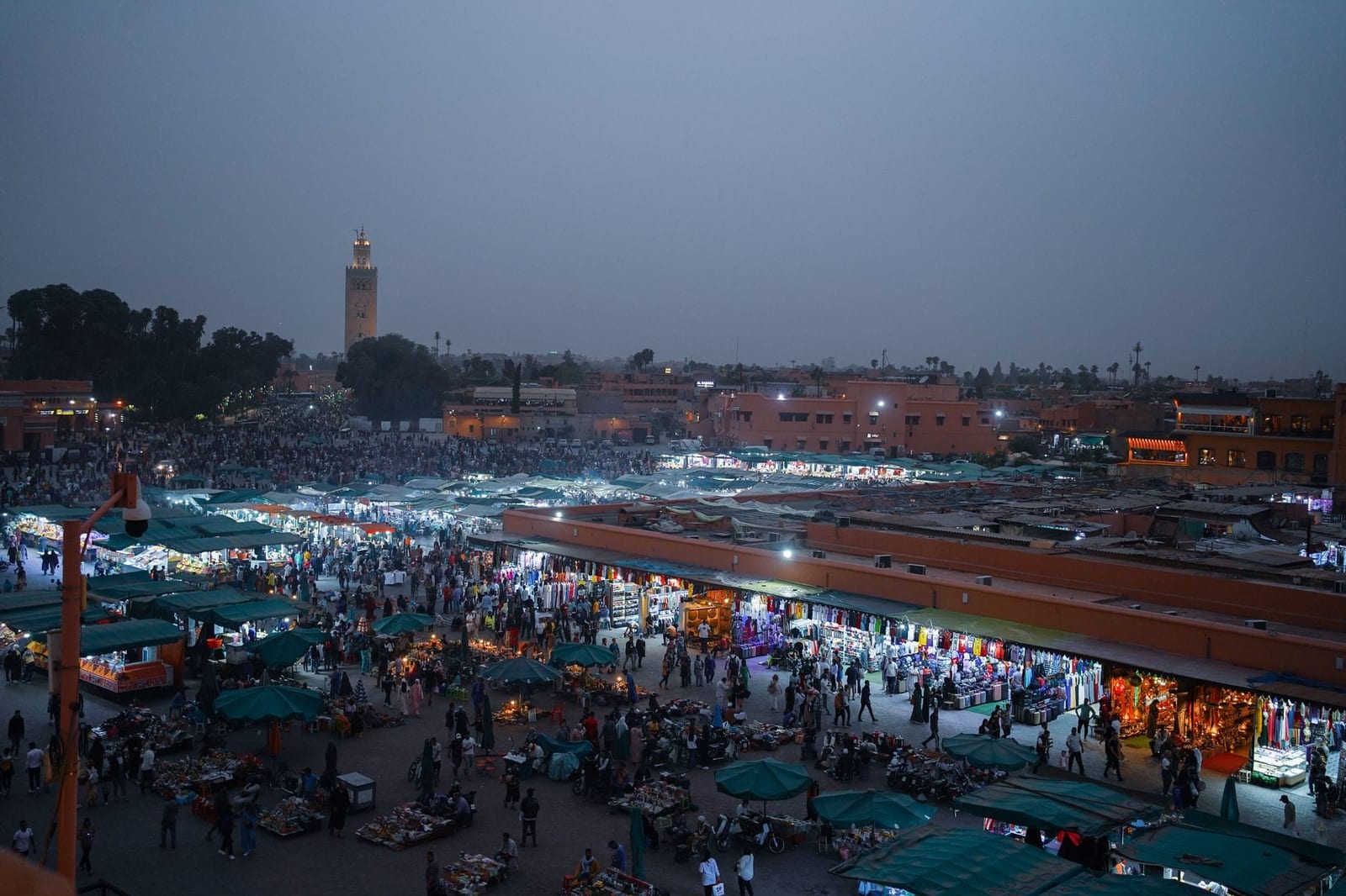 Menschen und Marktlichter auf dem Jemaa-el-Fnaa-Platz nach Sonnenuntergang
