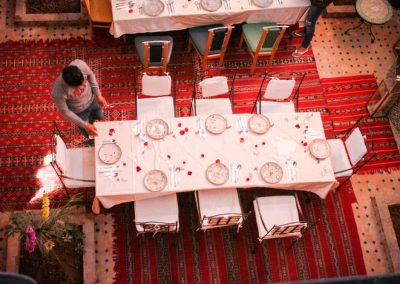 Gedeckter Tisch in einem Zimmer mit roten Teppichen und weiß gedecktem Geschirr für einen guten Start aus Marrakesch